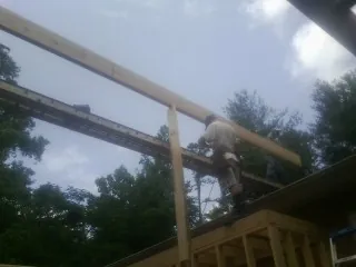 Carpenter setting a ridge beam over a new addition frame — Ice Dam Removal by Roofing Brothers in New Canton