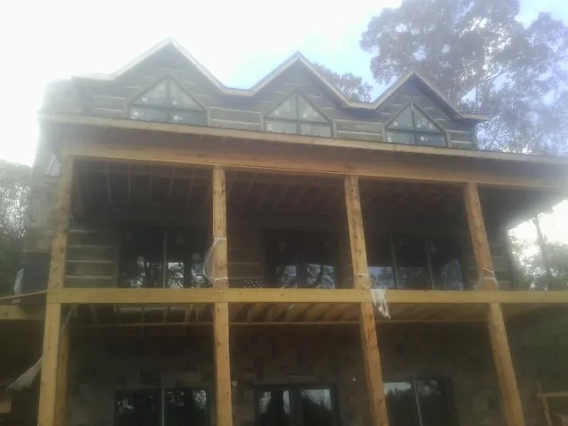 Dormers and porch framing on a large log home under construction — Roof Coating work by our crew in New Canton