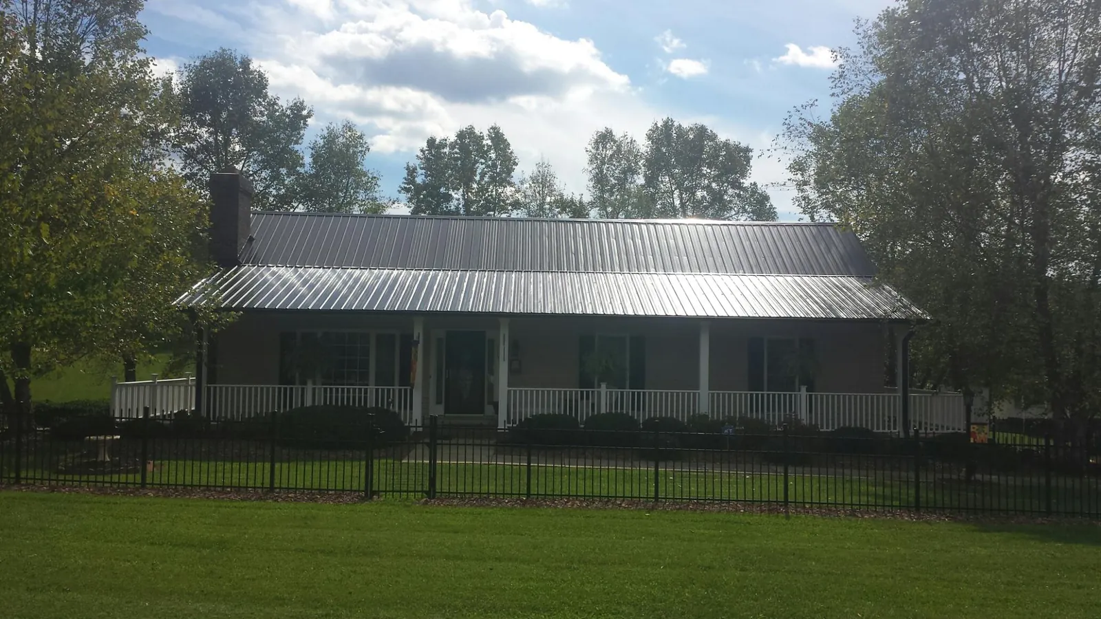 Gray metal roof on a brick ranch with a full width front porch — Gutter Guard Installation work by our crew in New Canton
