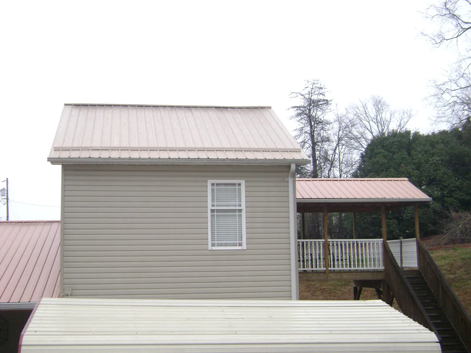 Tan metal roofs on a two story addition and attached porch, from a Roof Replacement job in New Canton